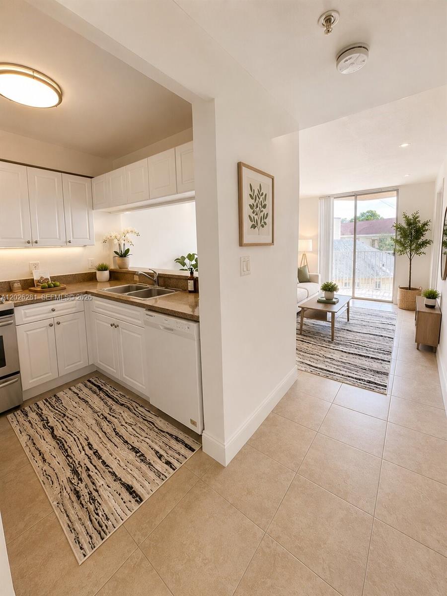A kitchen with white cabinets and granite countertops opens into a living area with balcony — 102 SW 6th Ave # 205, Miami FL 33130, MIAMI, FL