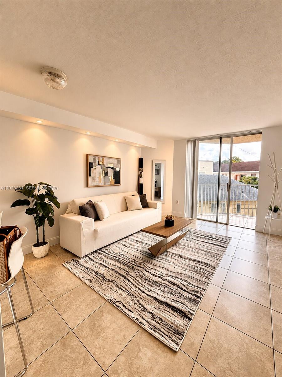 A living room features a white sofa, a patterned area rug, and a sliding glass door — 102 SW 6th Ave # 205, Miami FL 33130, MIAMI, FL