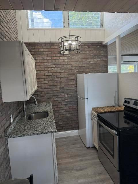 A kitchen features a brick wall, granite countertops, white cabinets, and a stainless steel stove — 131 S Federal Highway # 3, FL 33460, FL