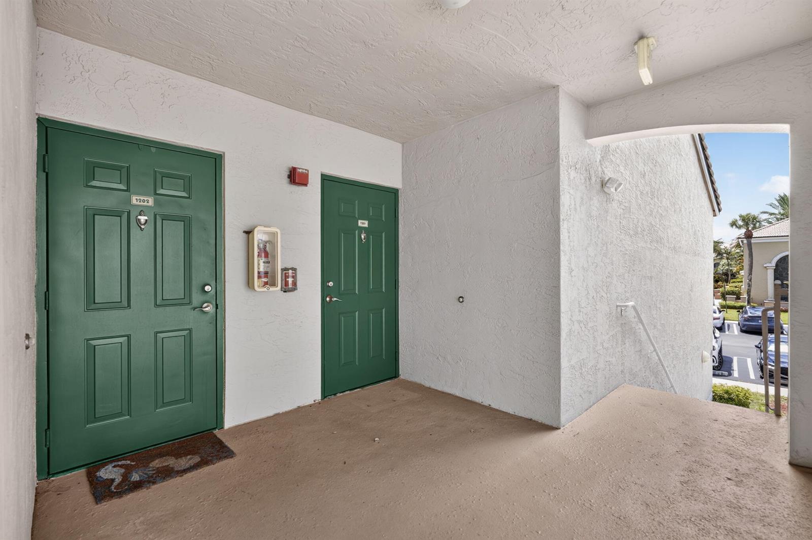 An exterior view of two green apartment doors with a fire extinguisher cabinet between them — 236 Village Boulevard, Tequesta FL 33469, TEQUESTA, FL