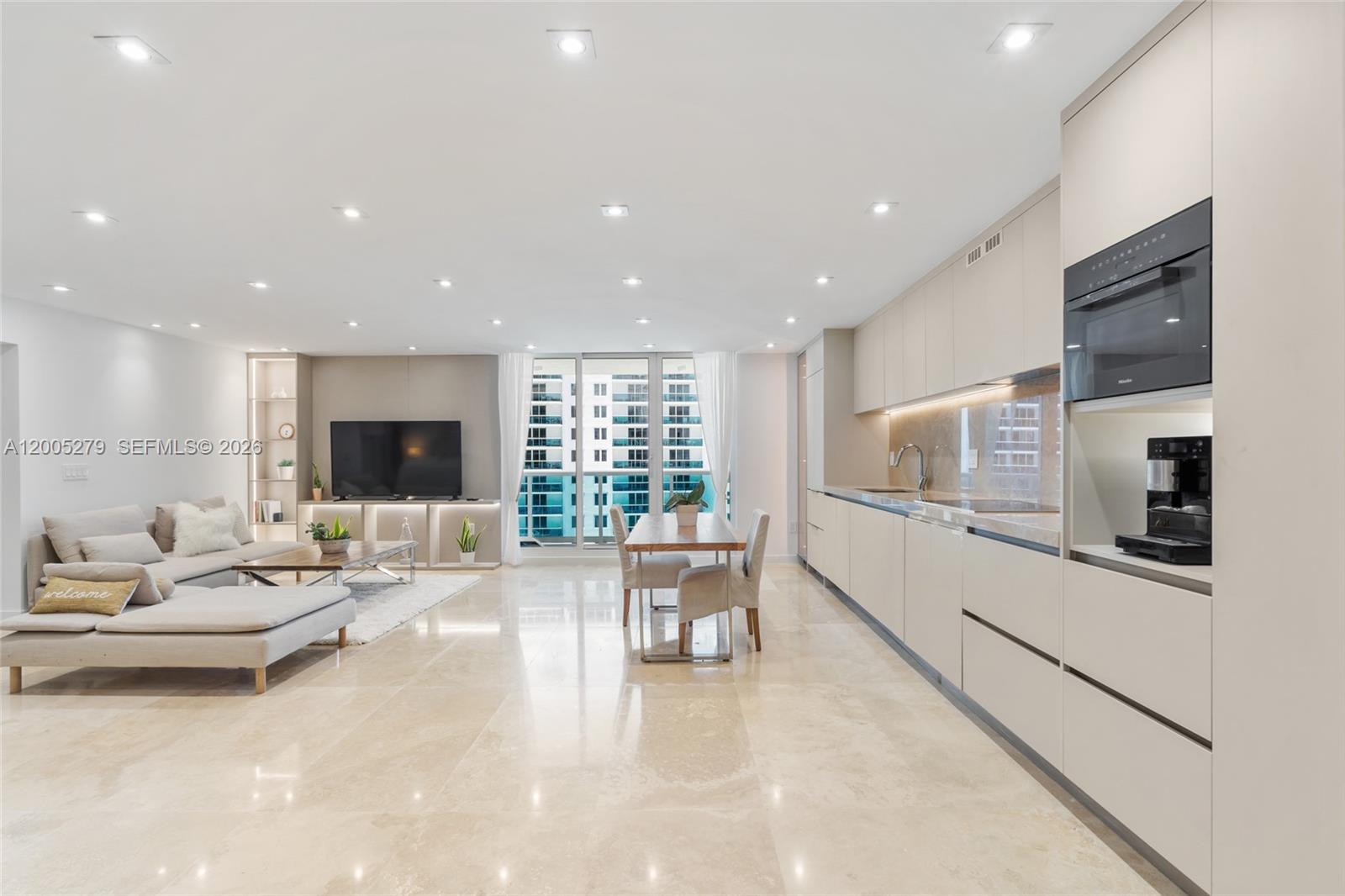A modern open-concept living area features a kitchen, dining space, and lounge with marble floors — 2301 Collins # 1011, Miami Beach FL 33139, MIAMI BEACH, FL