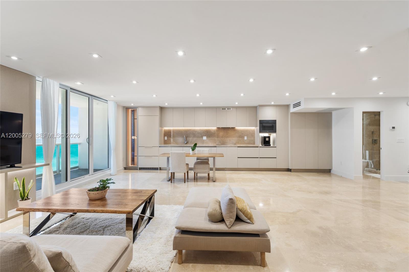A modern open-concept living area features a kitchen, dining space, and ocean views — 2301 Collins # 1011, Miami Beach FL 33139, MIAMI BEACH, FL