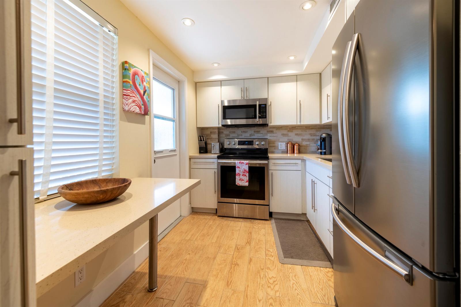 A kitchen features white cabinets, stainless steel appliances, a breakfast bar, and wood-look flooring — 2651 S Course Drive # 308, Pompano Beach FL 33069, POMPANO BEACH, FL