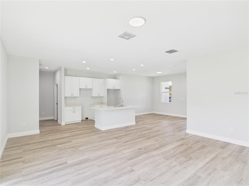 An open-concept kitchen features white cabinetry, a central island, and light wood-look flooring — 12807 SW 73RD AVENUE ROAD, OCALA, FL