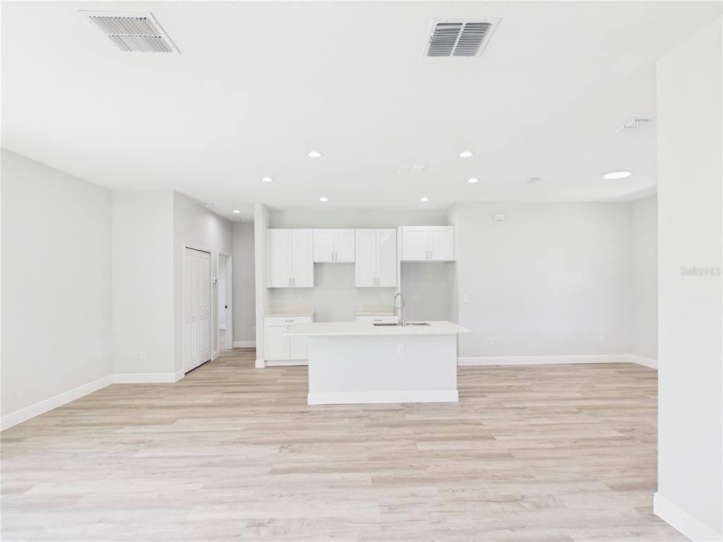 A bright, open-concept kitchen features white cabinetry, a central island, and light wood-look flooring — 12807 SW 73RD AVENUE ROAD, OCALA, FL