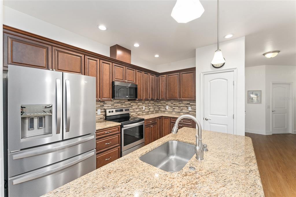 A kitchen features wood cabinets, granite countertops, stainless steel appliances, and a central island sink — 12938 NW 11TH PLACE, NEWBERRY, FL