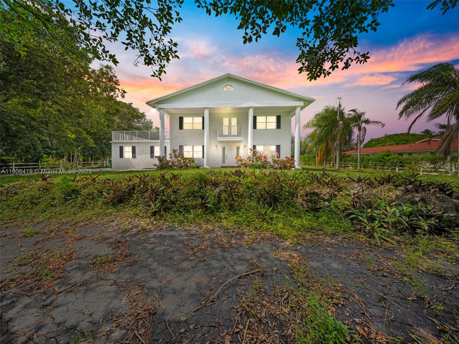 A two-story white house with a columned porch and a side balcony at sunset — 6365 NW 79th Way, Parkland FL 33067, PARKLAND, FL