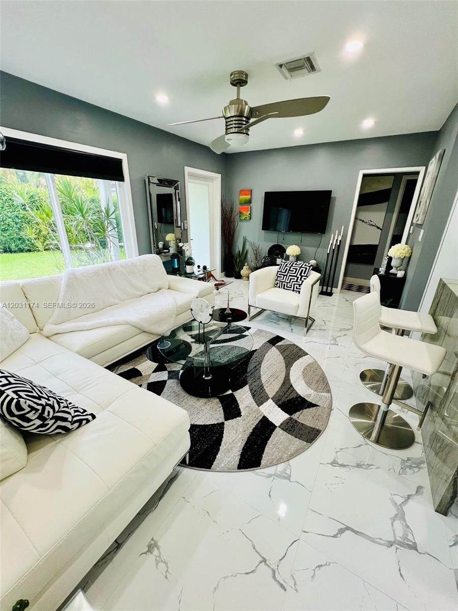 A modern living room features white leather furniture, a circular patterned rug, and marble flooring — 920 NE 108th St # 0, Biscayne Park FL 33161, BISCAYNE PARK, FL