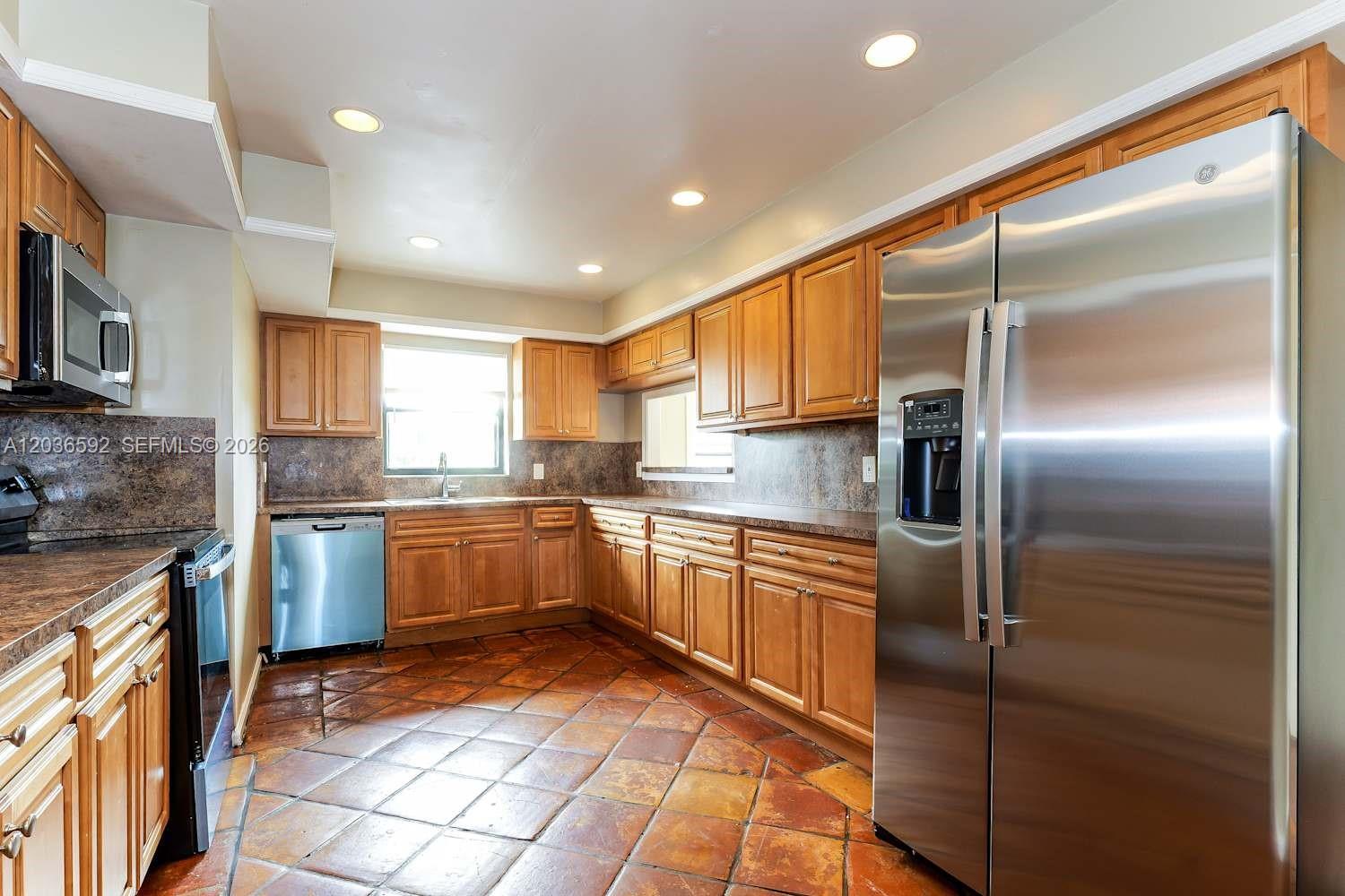 A kitchen with wood cabinets, stainless steel appliances, and brown tile flooring — BOYNTON BEACH, FL