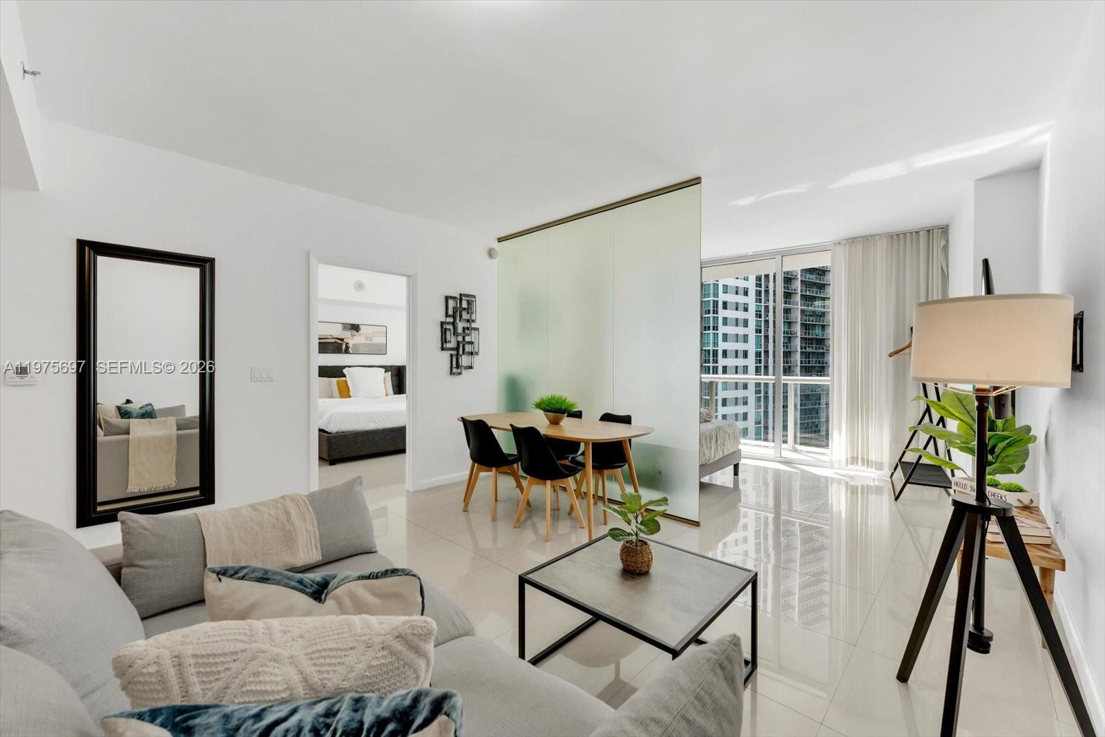 A modern living room and dining area feature white tile floors and a glass partition — 485 Brickell Ave # 1807, Miami FL 33131, MIAMI, FL