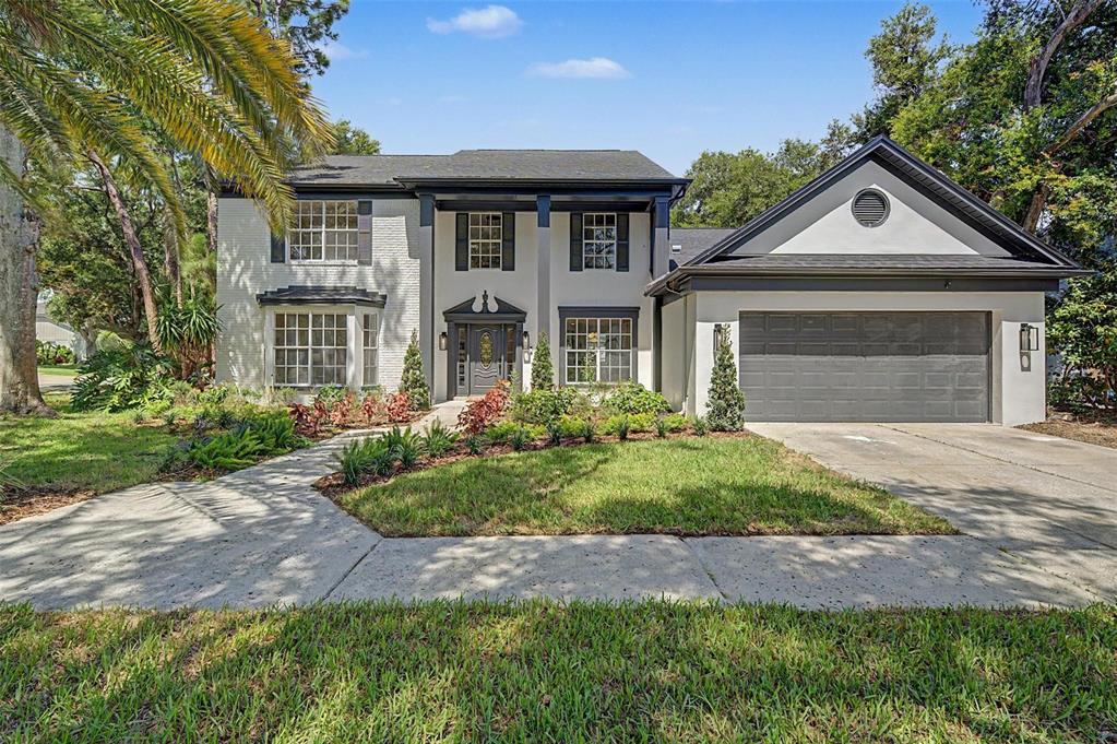 A two-story house with white brick, dark trim, a front walkway, and an attached garage — 15602 INDIAN QUEEN DRIVE, ODESSA, FL