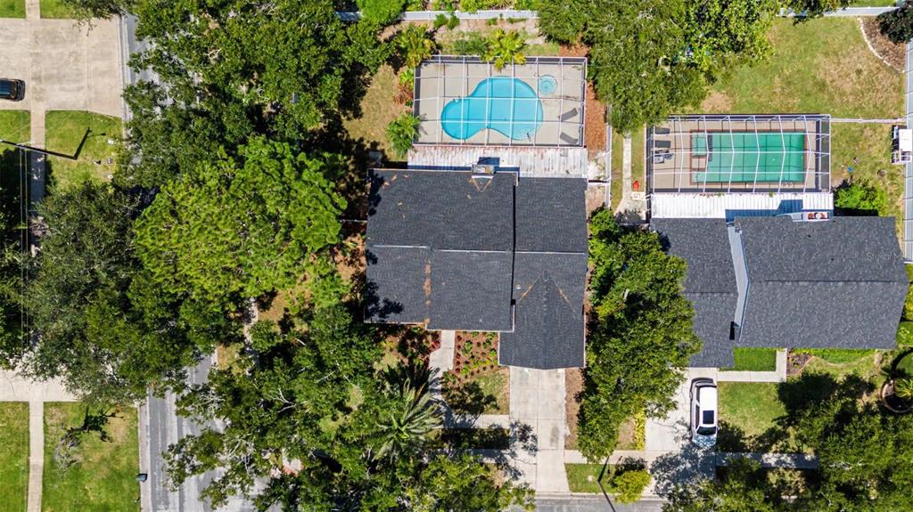An aerial view shows two houses with screened-in swimming pools surrounded by trees and lawns — 15602 INDIAN QUEEN DRIVE, ODESSA, FL