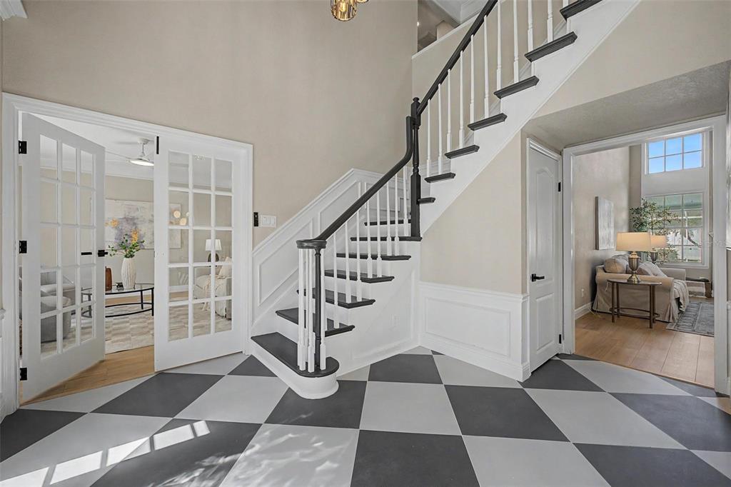 A foyer features a black and white checkered floor, a staircase, and two open doorways — 15602 INDIAN QUEEN DRIVE, ODESSA, FL