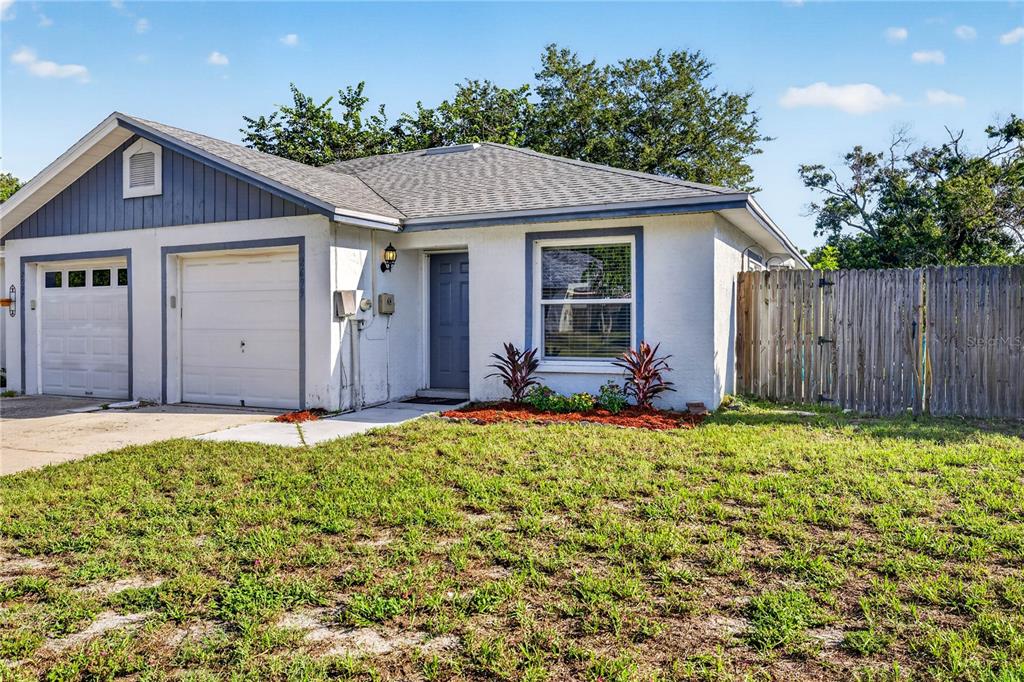 A single-story house with a white stucco exterior, a garage, and a wooden privacy fence — 2699 MACKLIN COURT, PALM HARBOR, FL