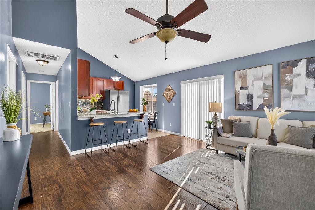 A living room and kitchen area with hardwood floors, blue walls, and a ceiling fan — 2699 MACKLIN COURT, PALM HARBOR, FL