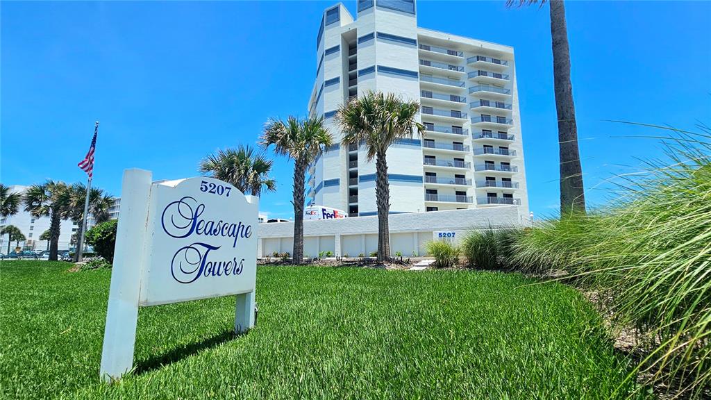 A white sign for Seascape Towers stands in front of a multi-story beachside apartment building — 5207 S ATLANTIC AVENUE UNIT 323, NEW SMYRNA BEACH, FL