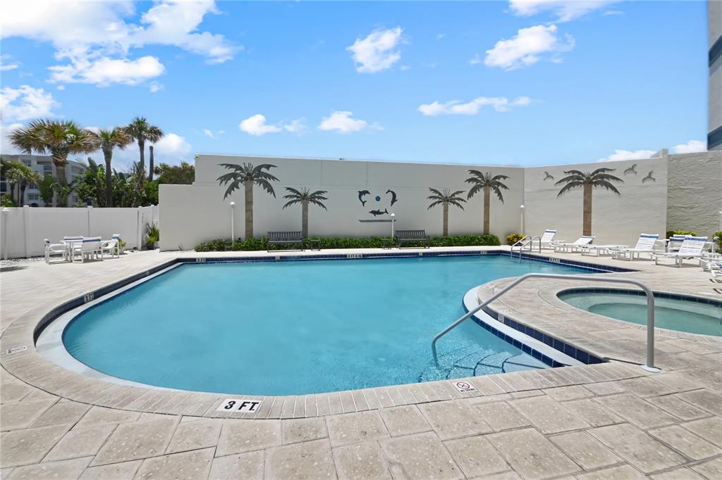 An outdoor swimming pool and hot tub are surrounded by a paved deck and wall — 5207 S ATLANTIC AVENUE UNIT 323, NEW SMYRNA BEACH, FL
