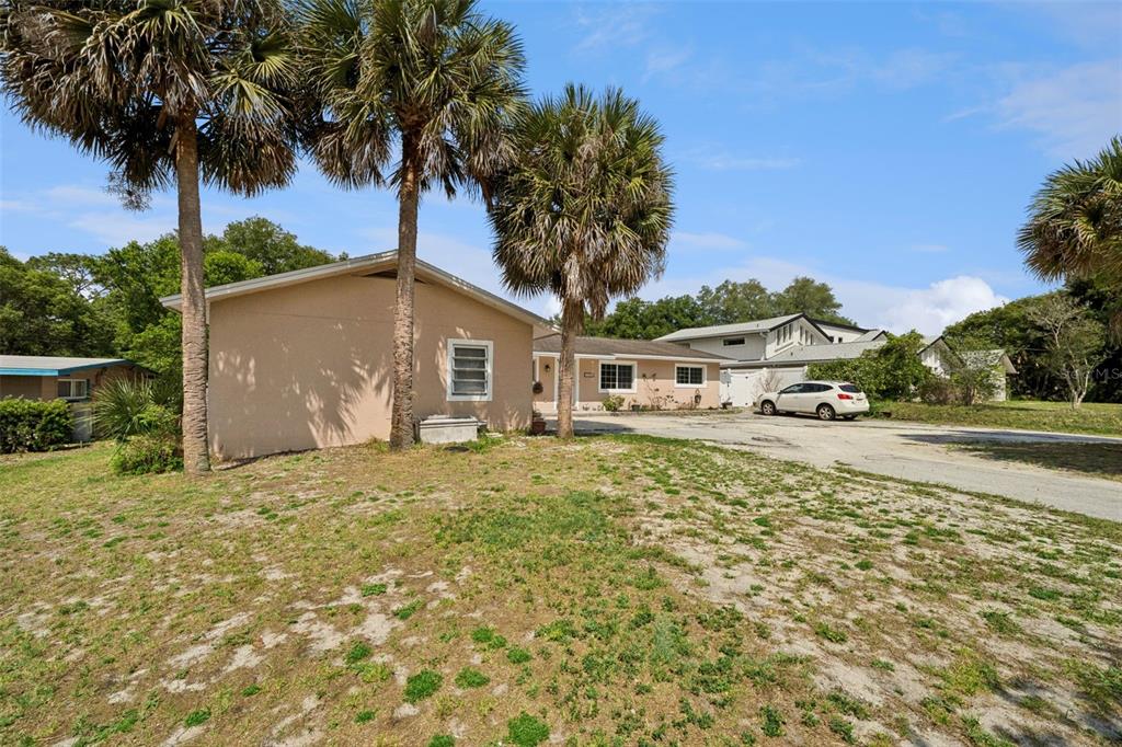 A tan single-story house with a gravel driveway and palm trees in the front yard — 1050 CRYSTAL BOWL CIRCLE, CASSELBERRY, FL