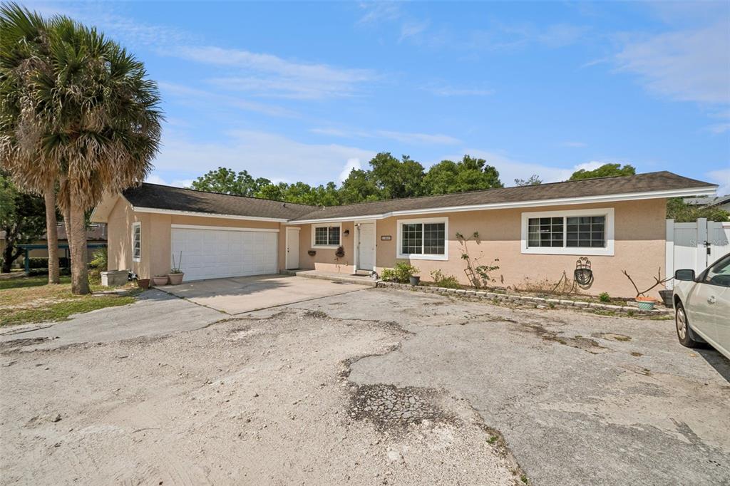 A single-story house with a beige stucco exterior, a two-car garage, and a large driveway — 1050 CRYSTAL BOWL CIRCLE, CASSELBERRY, FL
