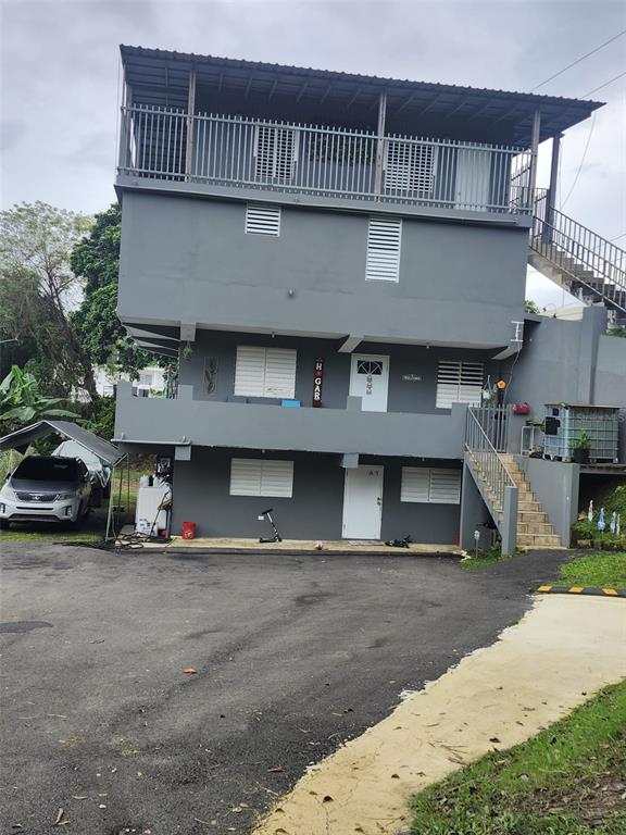 A three-story gray residential building with exterior staircases and a paved driveway — Bo. Ceiba LOS MELENDEZ, CIDRA, PR