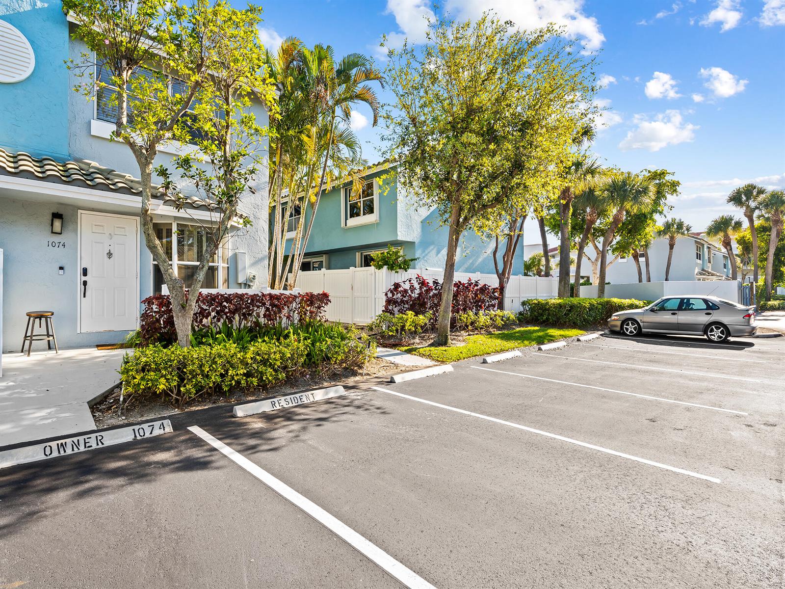A blue two-story townhouse exterior features a parking lot with designated owner and resident spaces — 1074 Jeffery Street, Boca Raton FL 33487, BOCA RATON, FL