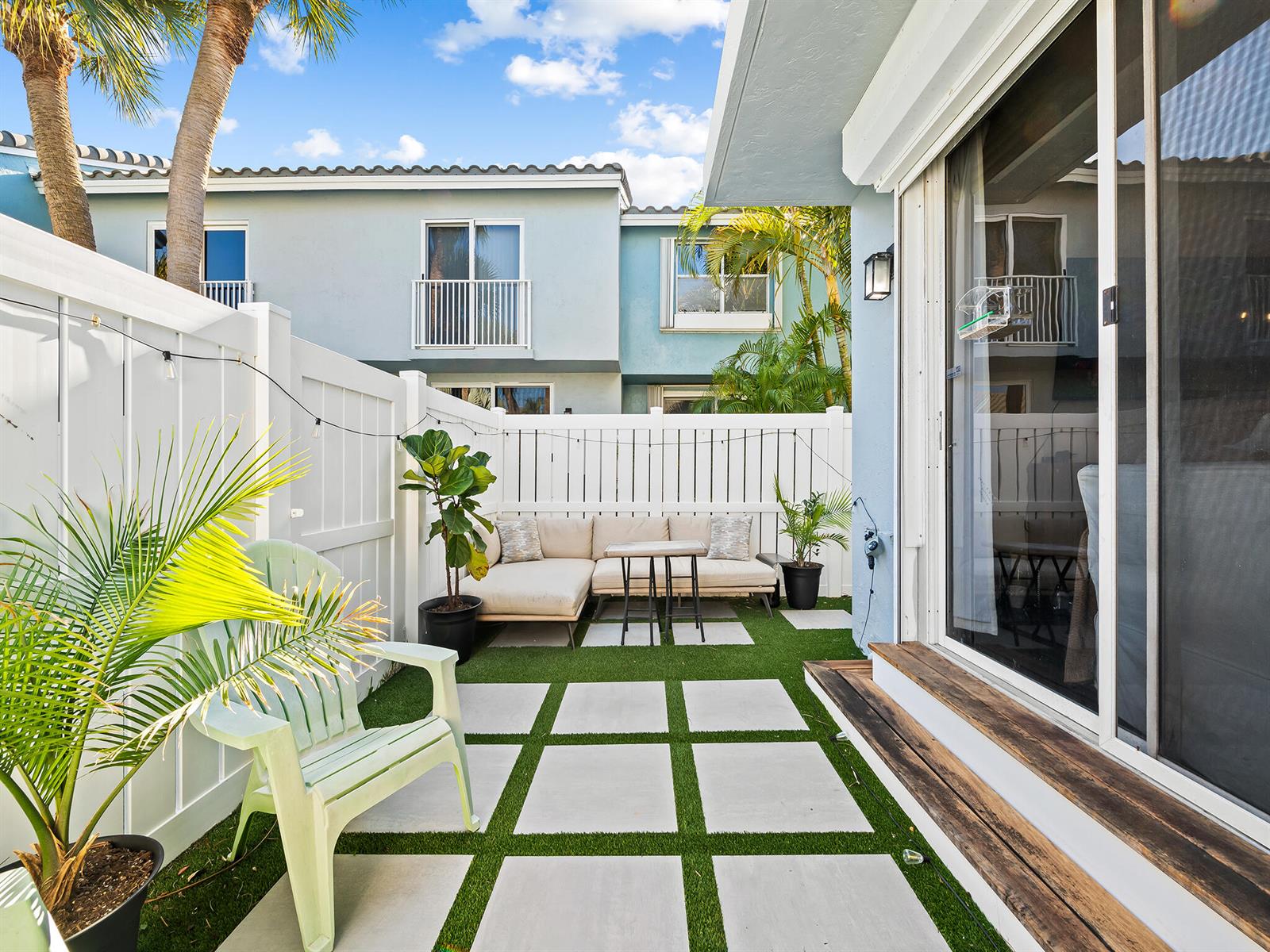 A small patio features artificial turf, square pavers, a sectional sofa, and a light-colored fence — 1074 Jeffery Street, Boca Raton FL 33487, BOCA RATON, FL