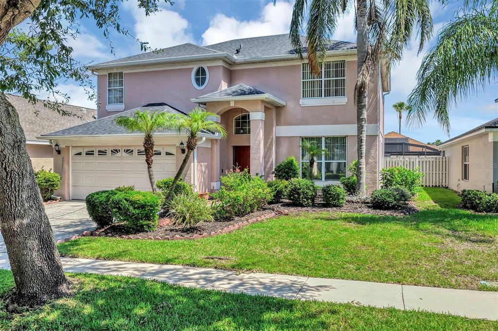 A two-story pink stucco house with a two-car garage and a front lawn — 4921 CASA VISTA DRIVE, ORLANDO, FL
