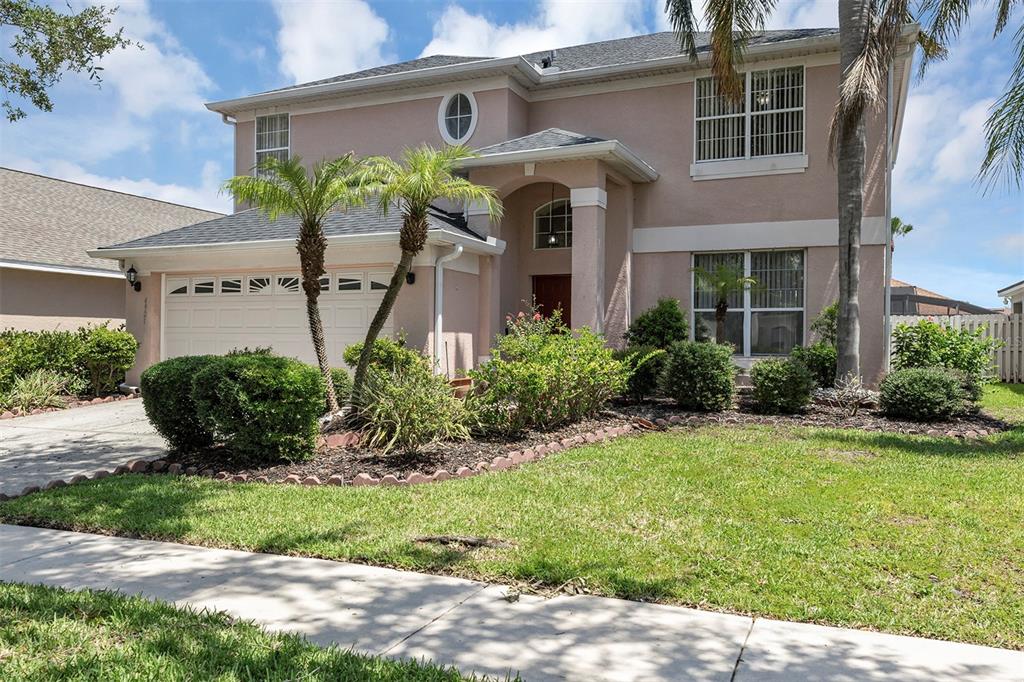 A two-story suburban house with a tan stucco exterior, a two-car garage, and palm trees — 4921 CASA VISTA DRIVE, ORLANDO, FL