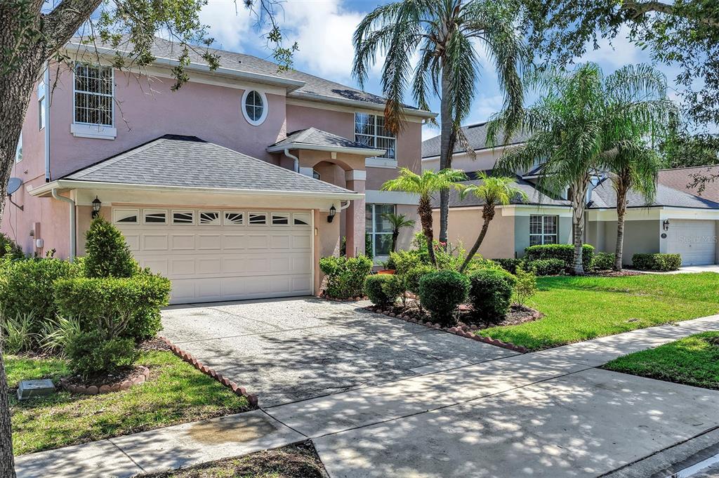A two-story pink house with a two-car garage and palm trees in the front yard — 4921 CASA VISTA DRIVE, ORLANDO, FL