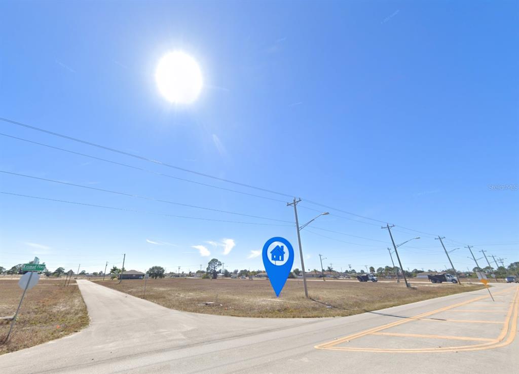 A vacant corner lot is marked with a blue house icon under a bright sun — 2326 NW 15TH PLACE, CAPE CORAL, FL