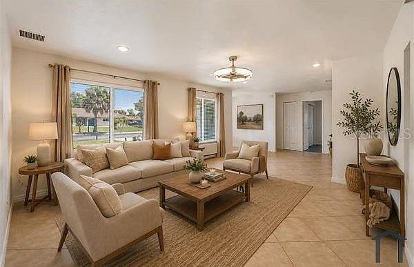 A living room features a beige sofa, two armchairs, a coffee table, and tile flooring — 4404 MEADOW CREEK CIRCLE, SARASOTA, FL