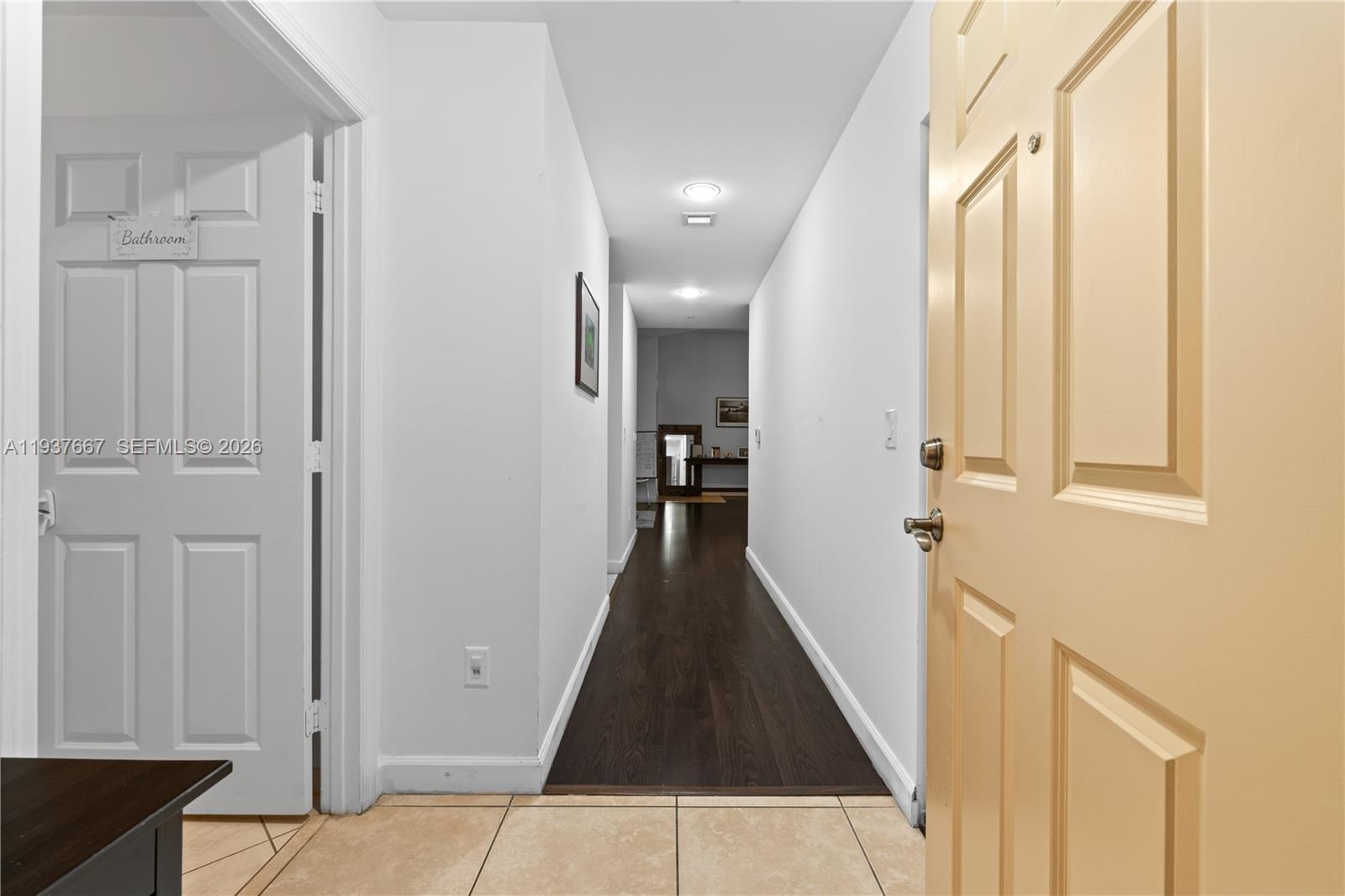 A hallway with dark wood flooring connects a tiled entryway to a distant room — 8395 SW 73rd Ave # 115, Miami FL 33143, MIAMI, FL