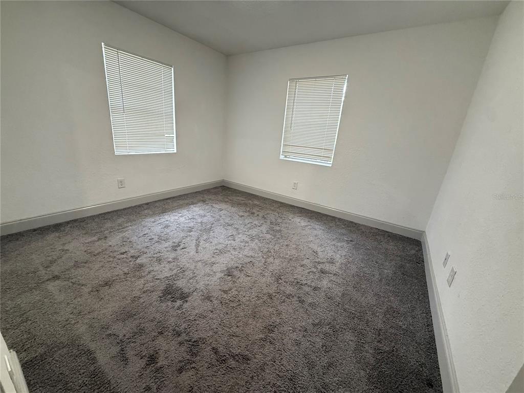 An empty bedroom features gray carpeting, white walls, and two windows with closed blinds — 13 VOLUSIA DRIVE, DEBARY, FL