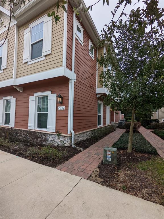 The exterior of a two-story building features red and tan siding with stone accents — 7532 SUNVILLE AVENUE, KISSIMMEE, FL