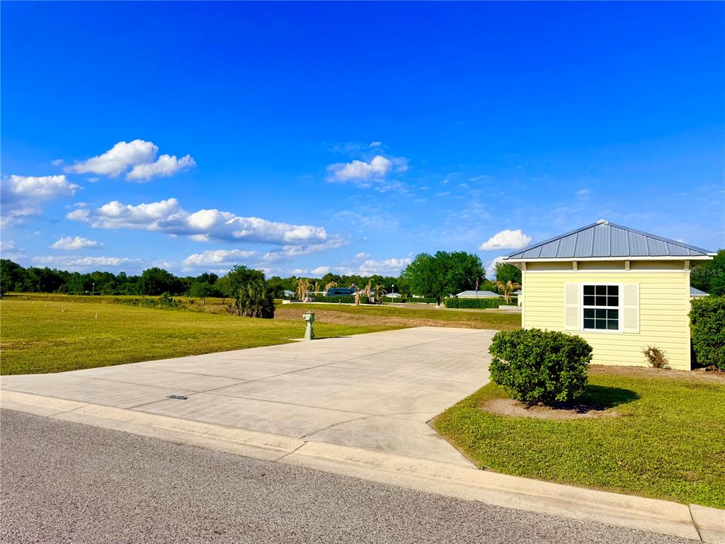 A concrete driveway leads to a small yellow building with a metal roof — 9381 SE 47TH WAY, WEBSTER, FL
