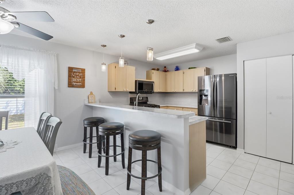 A kitchen features light wood cabinets, stainless steel appliances, a breakfast bar, and tile flooring — 4155 N LEE STREET, BEVERLY HILLS, FL