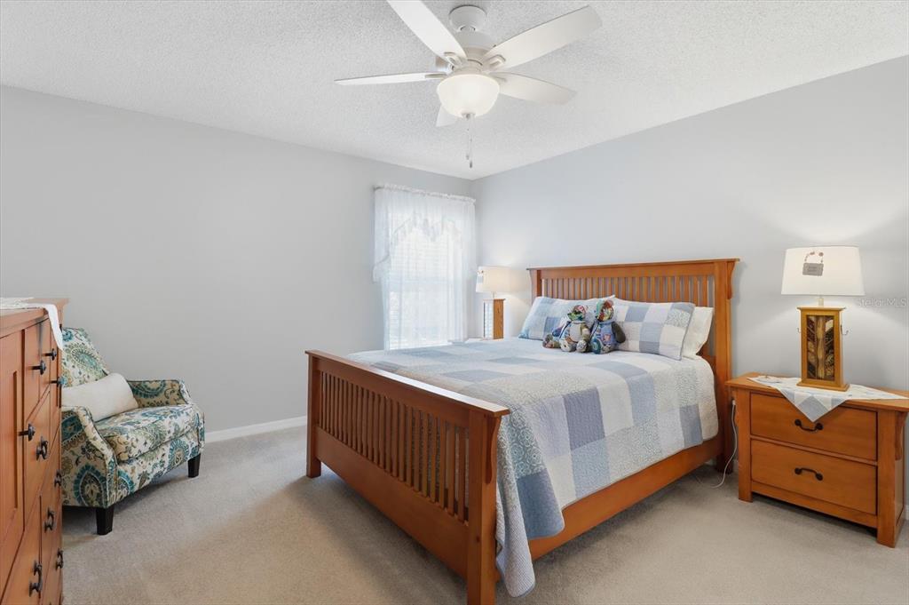 A bedroom features a wooden bed frame, a patterned armchair, and a ceiling fan — 4155 N LEE STREET, BEVERLY HILLS, FL