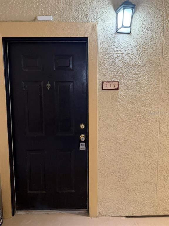 A black front door with a brass knocker and lockbox is labeled with the number 117 — 1321 ARBOR VISTA  LOOP UNIT 117, LAKE MARY, FL