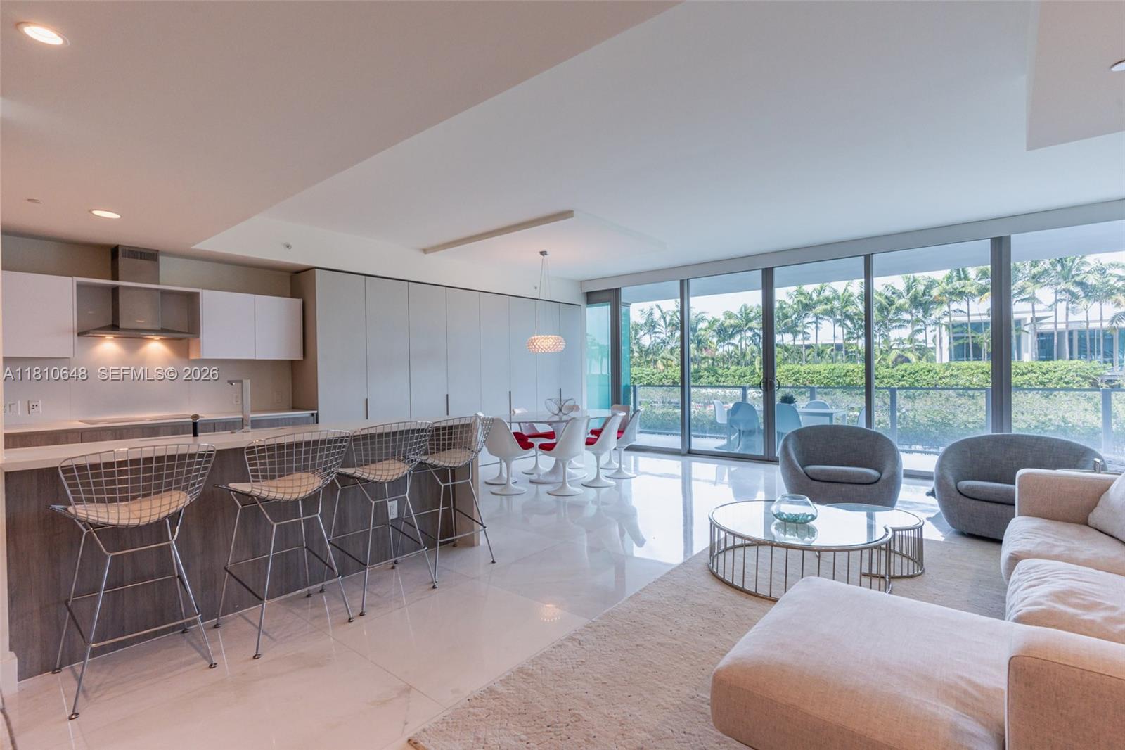 A modern open-concept living area features a kitchen with bar seating, dining space, and balcony — 360 Ocean Dr # 205S, Key Biscayne FL 33149, KEY BISCAYNE, FL