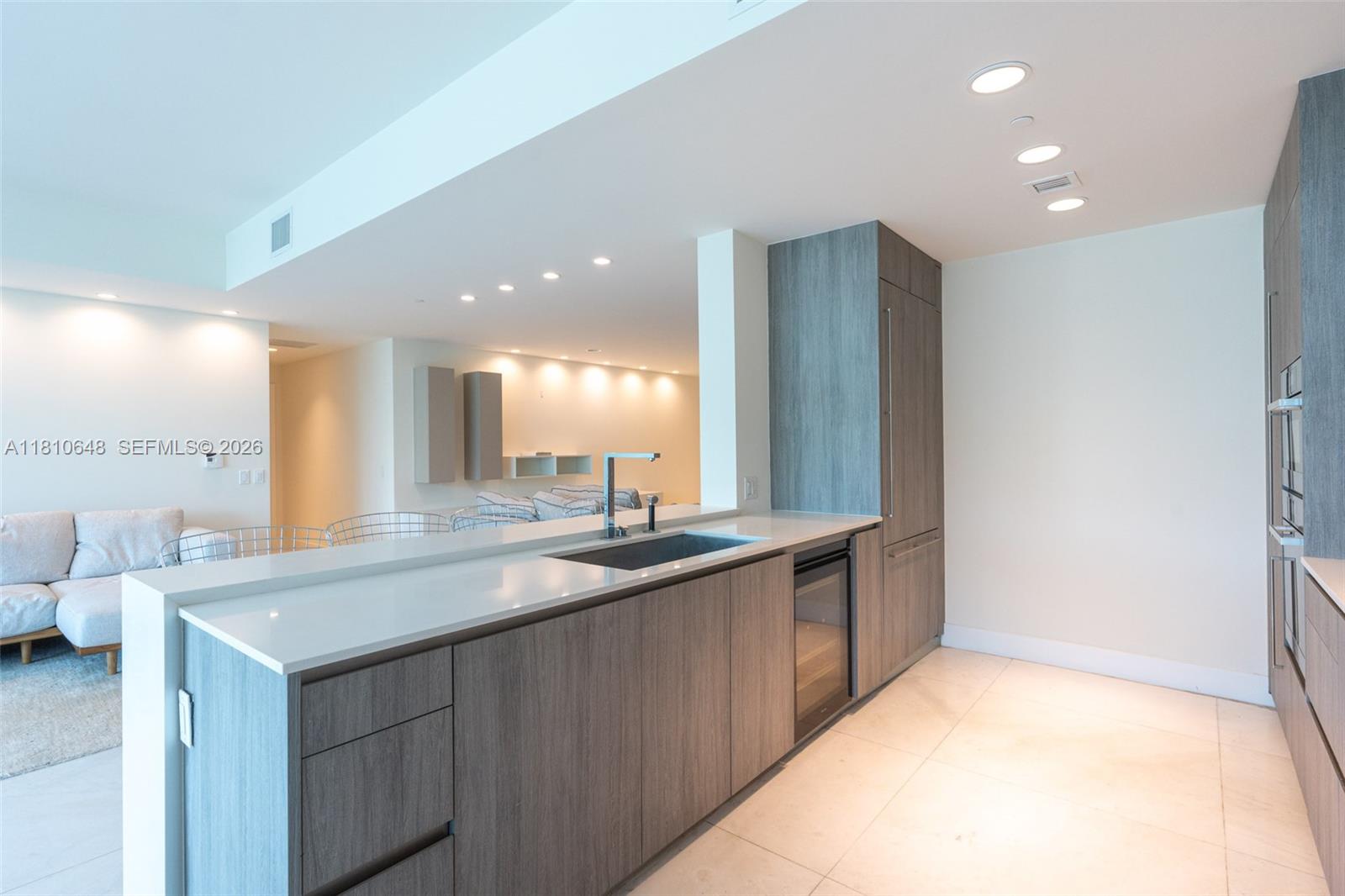 A modern kitchen features wood-grain cabinetry, white countertops, and a stainless steel sink — 360 Ocean Dr # 205S, Key Biscayne FL 33149, KEY BISCAYNE, FL