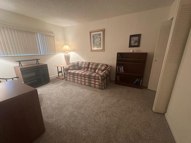 A carpeted living room features a plaid sofa, a wooden bookshelf, and a window with blinds — 2975 SW 22nd Avenue # 2020, Delray Beach FL 33445, DELRAY BEACH, FL