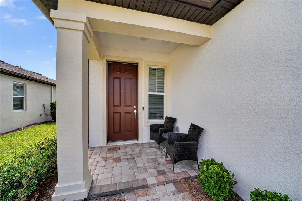 A covered front porch features a brown door, a window, and two black wicker chairs — 6043 SW 93RD CIRCLE, OCALA, FL