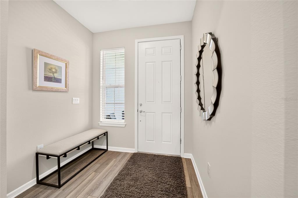 An entryway features a bench, a window with blinds, a mirror, and wood-look flooring — 6043 SW 93RD CIRCLE, OCALA, FL