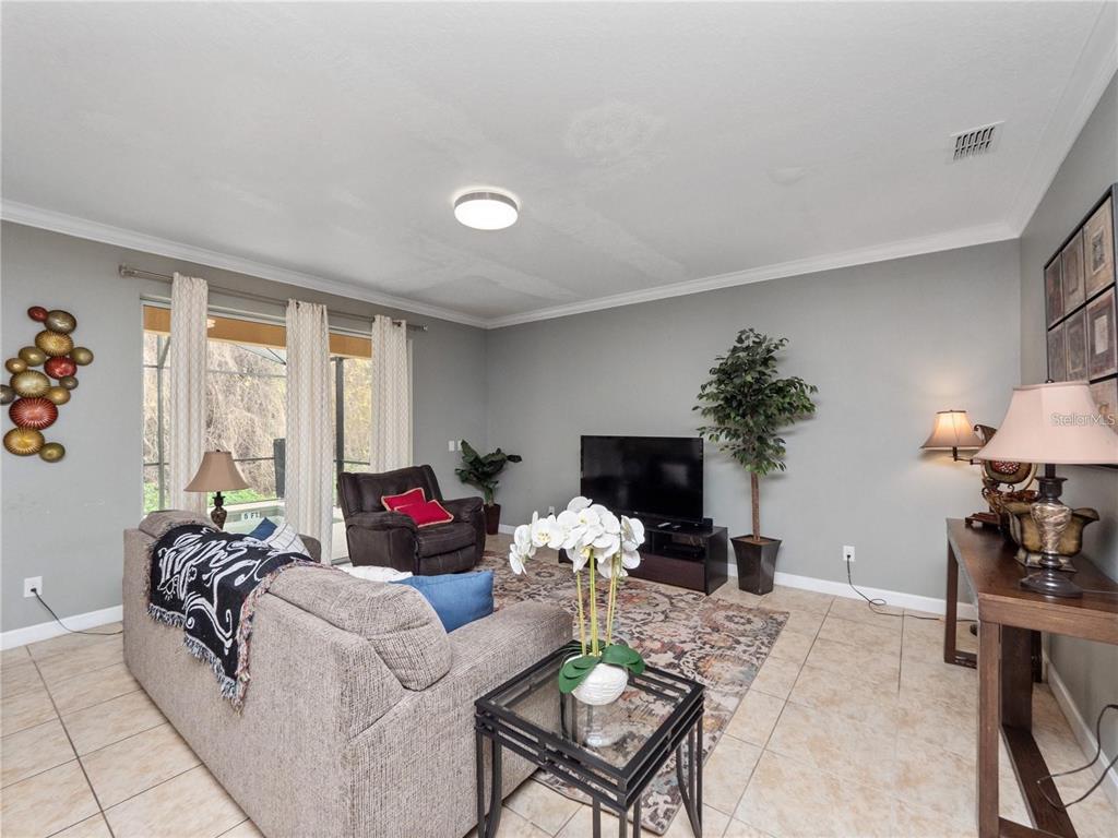 A living room features tile flooring, a grey sofa, a television, and a sliding glass door — 8876 CANDY PALM ROAD, KISSIMMEE, FL