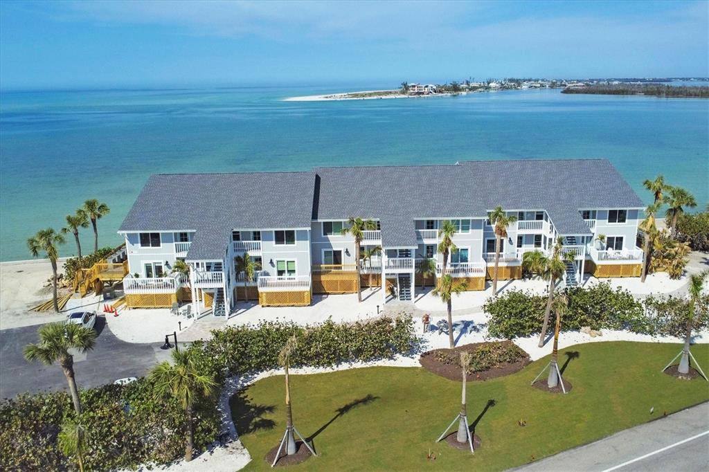 An aerial view of a multi-story, light-gray waterfront apartment building with a dark shingled roof — 6021 BOCA GRANDE CAUSEWAY UNIT G80, BOCA GRANDE, FL
