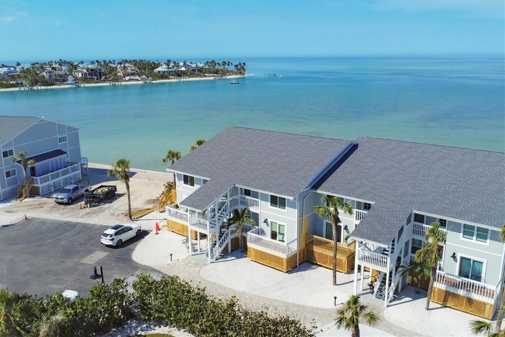 An aerial view shows a multi-story coastal apartment building with light siding near the water — 6021 BOCA GRANDE CAUSEWAY UNIT G80, BOCA GRANDE, FL