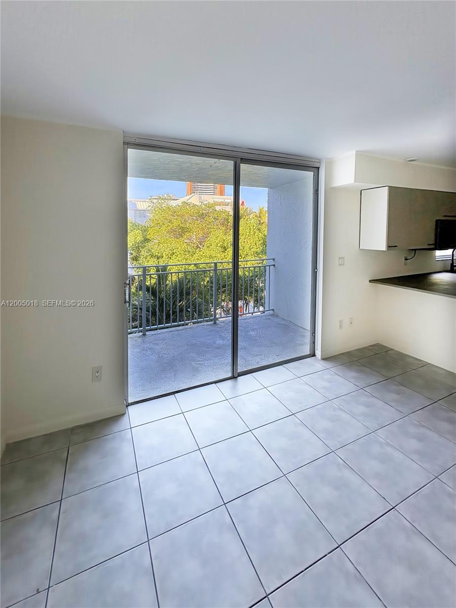 A tiled room features a sliding glass door leading to a balcony with outdoor greenery — 777 NE 62nd St # C402, Miami FL 33138, MIAMI, FL