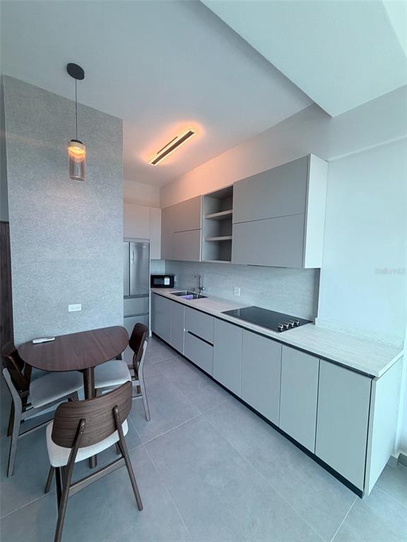 A modern kitchen features light gray cabinetry, a dark dining table, and a pendant light — 352 DEL PARQUE, SAN JUAN, PR