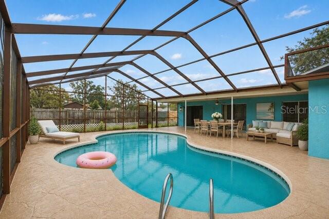 A screened-in patio features a swimming pool with a pink float and outdoor dining furniture — 8012 PAGODA DRIVE, SPRING HILL, FL