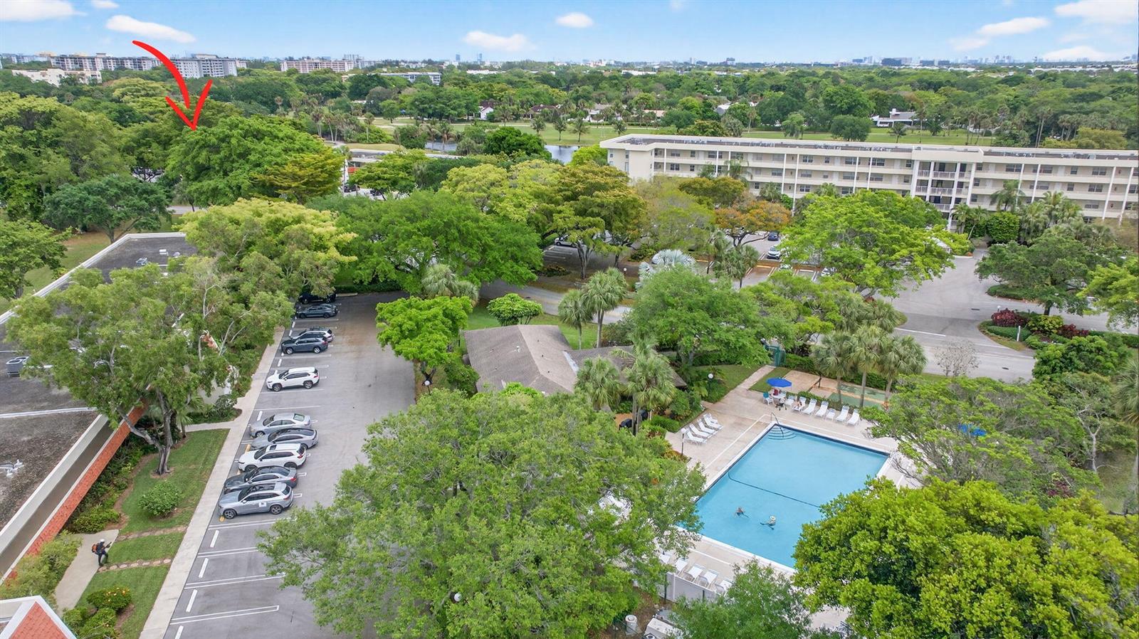 An aerial view shows a residential complex with a swimming pool, parking lot, and trees — 800 Cypress Boulevard # 204a, Pompano Beach FL 33069, POMPANO BEACH, FL